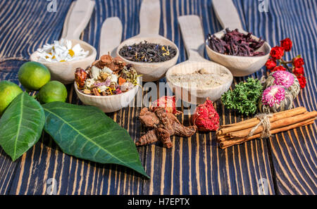 Fiori aromatici tè in cucchiaio su sfondo rustico Foto Stock