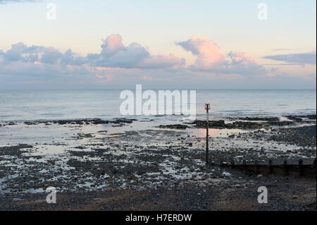 Tramonto sulla spiaggia di ciottoli con frangiflutti e boa segnaletica a Kingsdown, Kent Foto Stock