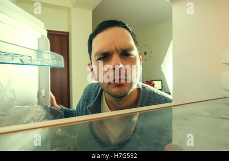 Uomo affamato con divertente faccia apre il frigo Foto Stock