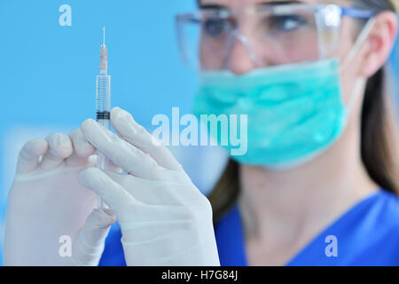 Il chirurgo dentista in maschera tenendo la siringa per iniettare anestesia. Foto Stock