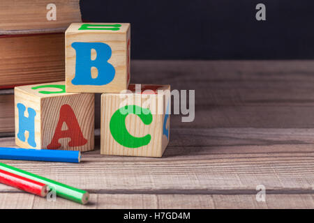 Bambini i blocchi in legno con lettere e matite colorate che giace su di un tavolo di legno. Primo piano. Foto Stock