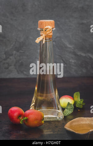 Aceto di mele. Bottiglia di apple aceto organico su sfondo rustico Foto Stock