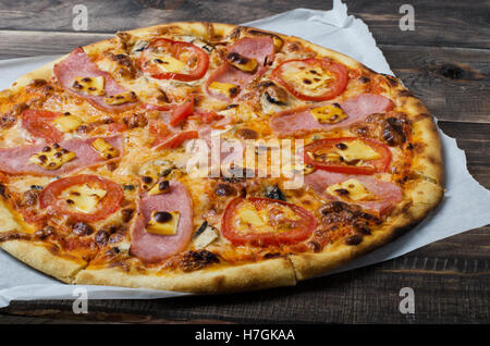 Pizza con pancetta e pomodori è su un tavolo di legno Foto Stock