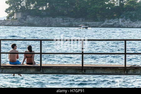 Due giovani seduti sul molo Foto Stock