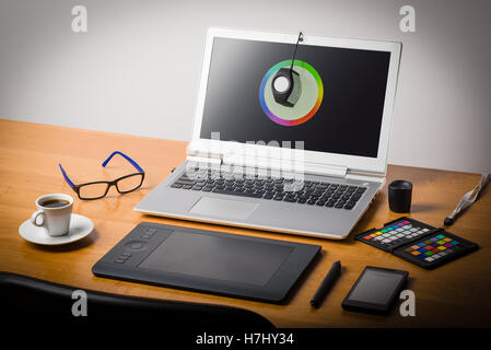 Fotografo dell'area di lavoro con il calibratore o Profiler è collegato al laptop display per ottenere la precisione dei colori Foto Stock