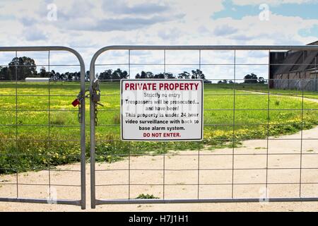 La proprietà privata cartello sulla porta di metallo, con paddock e storico hangar in background. Foto Stock