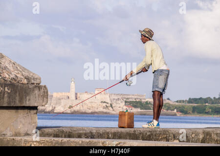 Pescatore cubano con asta sul Malecon nella parte anteriore del Castillo Foto Stock