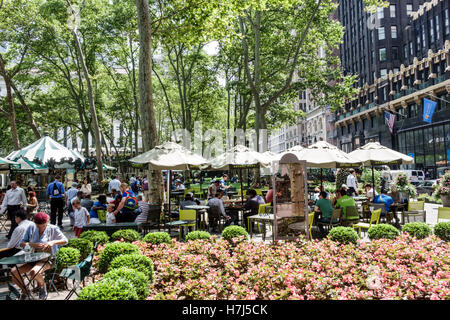 New York City,NY NYC Manhattan,Midtown,Bryant Park,parco pubblico,giochi da tavolo,posti a sedere,ombrelloni,aiuole,alberi,adulti,uomini maschio,donna female Foto Stock