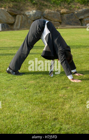 Imprenditore facendo yoga in un parco Foto Stock