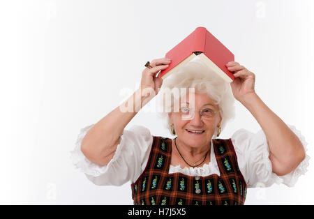 Allegro, donna anziana in possesso di un libro sopra la sua testa Foto Stock