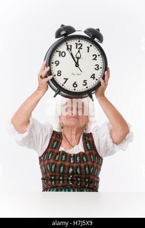 È quasi mezzogiorno, donna anziana in possesso di un orologio di allarme sulla sua testa Foto Stock