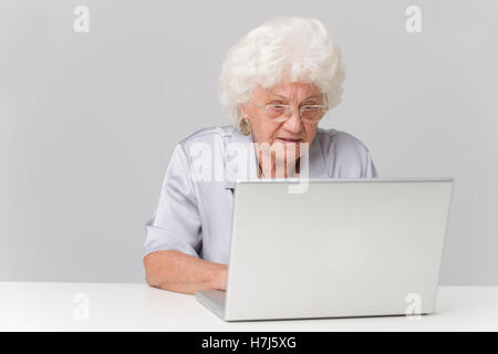 Donna anziana usando un computer portatile Foto Stock