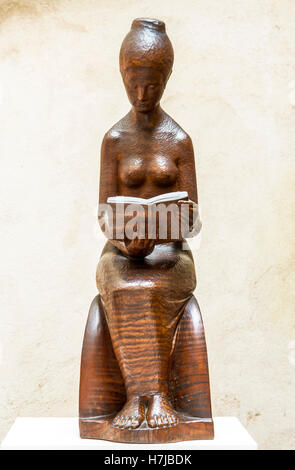 Il lettore, donna che legge un libro, scultura in legno di mogano dello scultore francese Jean Henninge Foto Stock