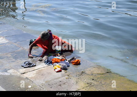 Donna indiana il lavaggio di vestiti nell'acqua del lago Pichola in Udaipur, Rajasthan, India Foto Stock