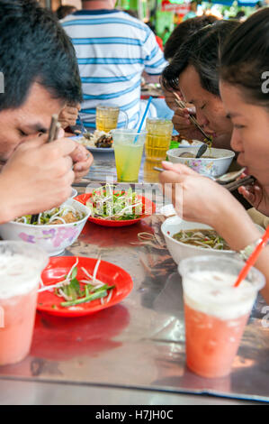 Gli ospiti presso il marciapiede diner Bun Mam Dac San mangiare Bun Mam, una piccante fermentare la zuppa di pesce e un sud delicatezza vietnamita di Saigon. Il Vietnam. Foto Stock