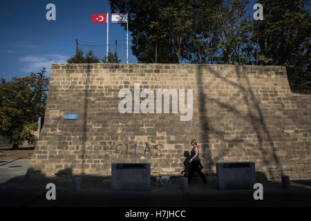 Nicosia, Cipro. 28 ott 2016. Nicosia, l'ultima capitale europea divisa dell'Europa. Una donna cammina con il cane acrossing le mura venete della città. Al di sopra ci sono il turco e la Repubblica turca di Cipro del Nord bandiere. © Sahan Nuhoglu/Pacific Press/Alamy Live News Foto Stock