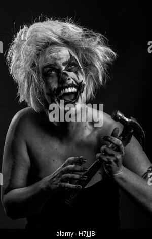 Blonde modello femminile come cruenti, impazzito Insane Clown omicida con un martello, in bianco e nero Foto Stock