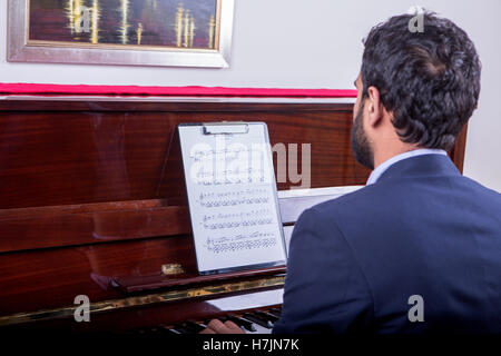 L'uomo suonando piano tune da note durante la seduta, barba uomo marrone Foto Stock