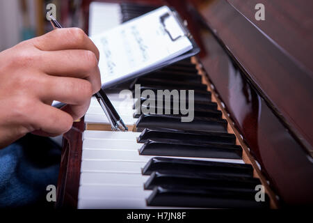 L'uomo suonare il pianoforte con penna a sfera nella mano destra e tenendo note nella mano sinistra penna capovolta Foto Stock