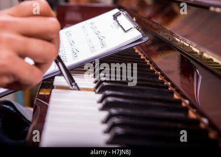 L'uomo gioca pianowith penna a sfera nero note nella mano sinistra Foto Stock