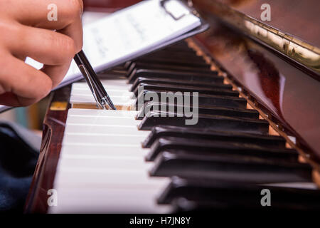 L'uomo suonando piano sintonia con penna a sfera penna in mano destra da notes Foto Stock