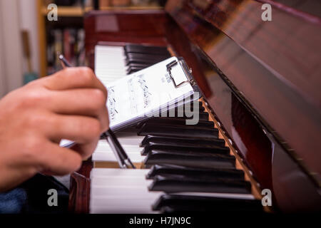L'uomo suonando piano sintonia con penna a sfera penna in mano destra da notes Foto Stock