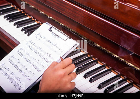 L'uomo suonando piano sintonia con penna a sfera nella mano destra da notes penna nera Foto Stock