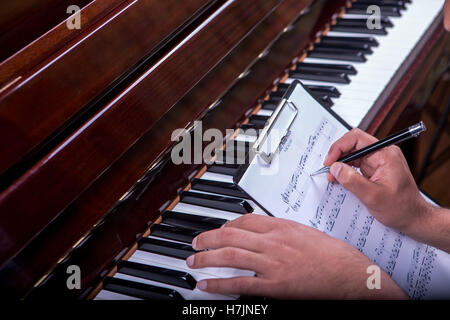 L'uomo suonando piano tune e tenendo i nodi scrivere appunti con penna a sfera nera penna Foto Stock