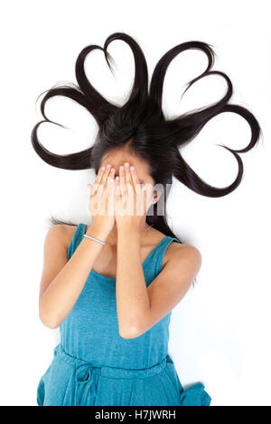 Ritratto di un giovane adolescente asiatico con le mani sul viso e capelli lunghi modellati a forma di cuore. Idea concettuale. Isolato su bianco Foto Stock