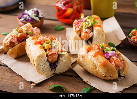 Hot Dog - sandwich con salsa messicana su sfondo di legno. Foto Stock