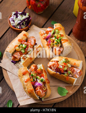 Hot Dog - sandwich con salsa messicana su sfondo scuro. Foto Stock