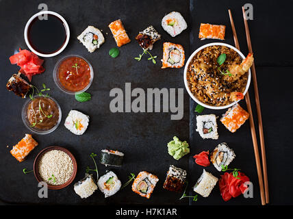 Tradizionale cibo giapponese - sushi, rotoli, Riso con gamberi e salsa su uno sfondo scuro. Vista superiore Foto Stock
