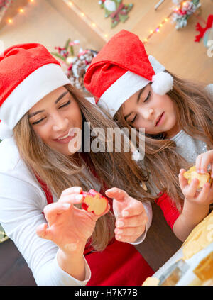 Ritratto di una madre amorevole insegnamento sua figlia piccola per rendere dolci fatti in casa, lo zenzero di cottura del pane e biscotti di Natale Foto Stock