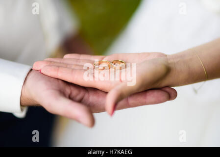 Close up brode e groom la mano che regge due anelli di nozze Foto Stock
