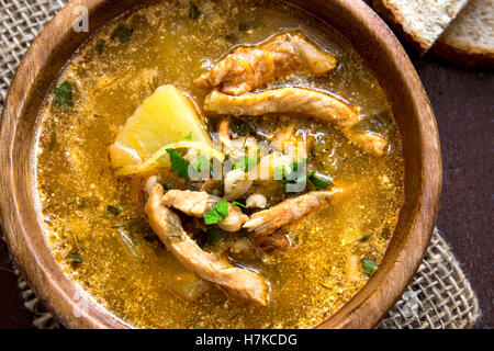 Inverno in casa tradizionale zuppa di carne con verdure e cereali in ciotola di legno su tavolo rustico Foto Stock