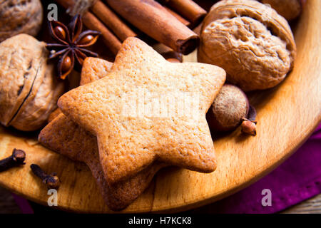 Natale rustico gingerbread cookie, i dadi e le spezie di Natale su piatto di legno vicino fino Foto Stock