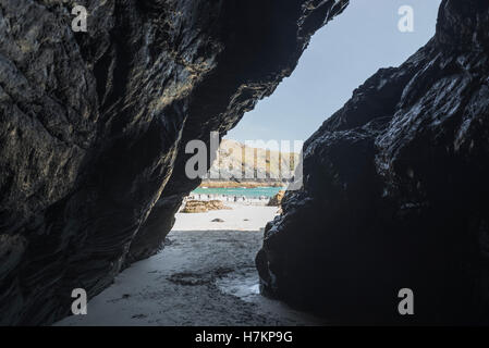 Guardando fuori una grotta buia nella costa rocciosa al sole sulla spiaggia di sabbia di Kynance Cove sulla penisola di Lizard presso la costa sud di cornwall, Regno Unito Foto Stock