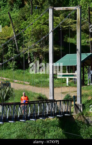 Un uomo che cammina sul ponte di sospensione in Karangahake Gorge, NZ. Foto Stock