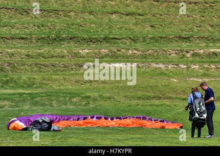 Imparare il parapendio con un coloratissimo paracadute sgonfiato in appoggio sull'erba. Foto Stock