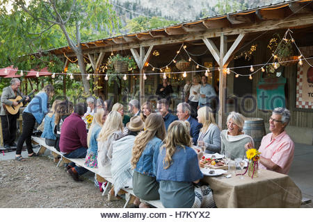 Gli amici sorseggiando outdoor harvest dinner party a lunga tavola patio