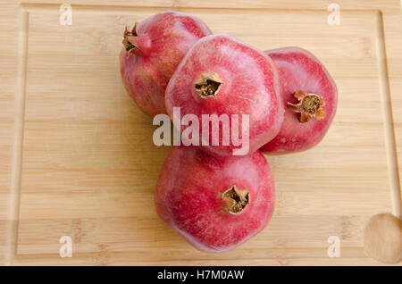 Pila di tre frutti di melograno sul tagliere di legno Foto Stock