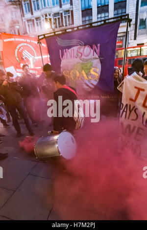 Londra, Regno Unito. 5 novembre 2016. Un detergente alla protesta calci lontano un fumo rosso flare dalla loro protesta in Oxford St al di fuori di John Lewis. Pulitori' union Regno voci del mondo e sostenitori esigono che la società di trattare la sua pulitori abbastanza sulla stessa base degli altri membri del personale che vi lavora. John Lewis è orgogliosa della sua " partnership " modello, sotto che coloro che lavorano nei loro negozi ottenere una quota dei loro profitti, ma le persone che tengono i negozi pulite sono trattati come cittadini di seconda classe, esclusi dalla annuale "bonus" con salari solo pochi pence al di sopra del minimo nazionale a £ 7. © Peter Mar Foto Stock