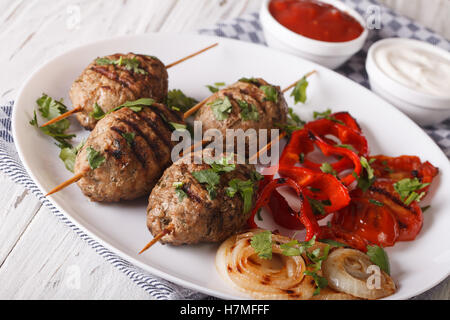 Kofte kebab con verdure alla griglia su una piastra e salsa di close-up sul tavolo. Posizione orizzontale Foto Stock