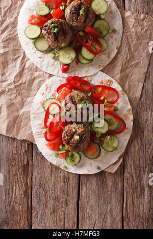 Carne alla griglia sfere con verdure fresche su un pane piatto sul tavolo. Vista verticale da sopra Foto Stock