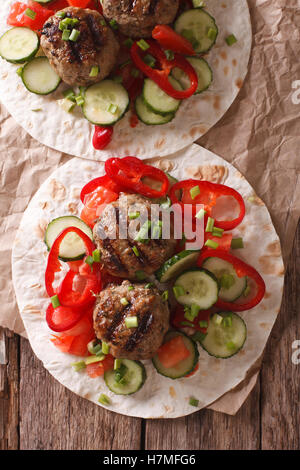 Carne alla griglia sfere con verdure fresche su un pane piatto vicino sul tavolo. Vista verticale da sopra Foto Stock