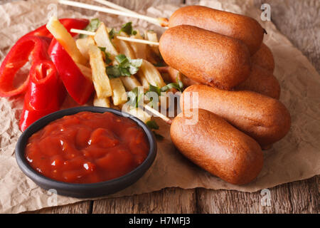 I cani di mais, patate fritte, pepe e ketchup sul tavolo di close-up orizzontale. Foto Stock