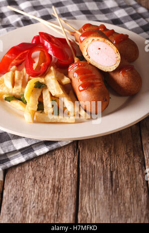 Cane di mais con le patatine fritte e le verdure su una piastra vicino sul piano verticale. Foto Stock