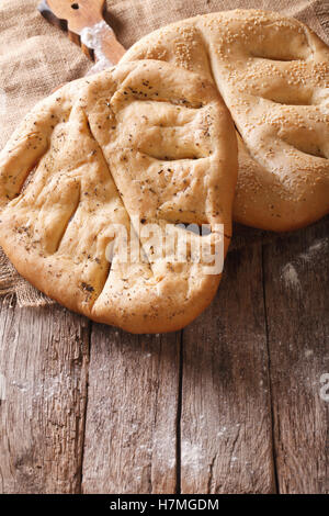 Fugasse pane francese con i semi di sesamo ed erbe closeup sul tavolo. verticale, rustico Foto Stock