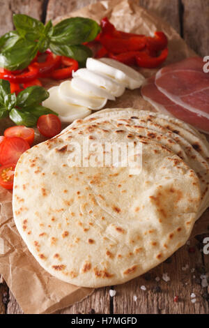 Italian piadina pane piatto, prosciutto, formaggio e verdure vicino sul piano verticale. Foto Stock