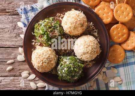 Cottage cheese sfere con cracker, erbe e semi di zucca close-up su una piastra orizzontale di vista da sopra Foto Stock